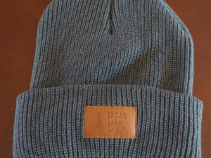 gray beanie with brown patch saying "cedar lake camp"