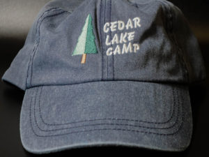 blue hat with pine tree and "cedar lake camp" title